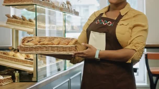 Kobiece baker gospodarstwa kosz z desery i ciasta pozowanie wesoły jej piekarni, uśmiechając się do kamery szczęśliwie przyjazną obsługę zawód interesu Sklep sklep pozytywności pyszne koncepcji - Materiał filmowy, wideo