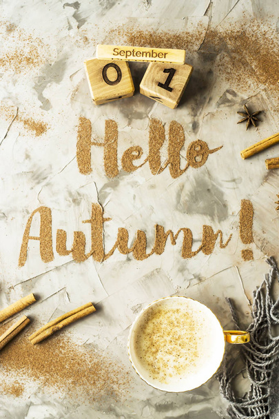 Γεια σας, το φθινόπωρο. Η φράση γράφεται με κανέλα σε γκρι φόντο. Δίπλα στο ξύλινο ημερολόγιο στο οποίο η ημερομηνία είναι η 1η Σεπτεμβρίου. Το Top view, επίπεδη lay - Φωτογραφία, εικόνα