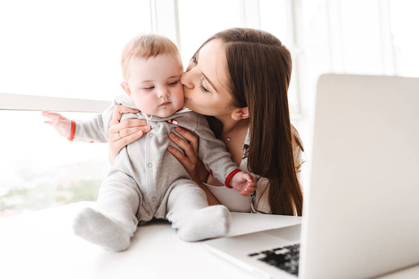 Image of happy young woman mother using laptop computer with her little child son indoors at home. - Valokuva, kuva