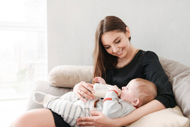 Image of happy young family. Mother feeds her little child indoors at home. - Valokuva, kuva