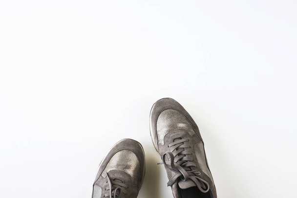 Sneakers grigie femminili argentate su sfondo bianco. Concetto moda autunno. Vista dall'alto, disposizione piatta, spazio di copia
 - Foto, immagini