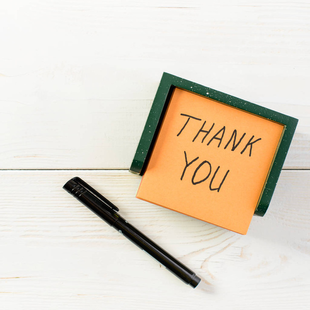Thank you written on post note sticker with pen on light wooden  - Фото, изображение