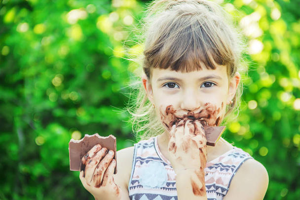 Ένα παιδί με γλυκά δόντια τρώει σοκολάτα. Επιλεκτική εστίαση. φύση. - Φωτογραφία, εικόνα