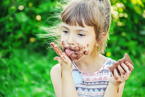 A sweet-toothed child eats chocolate. Selective focus. nature. - Foto, imagen