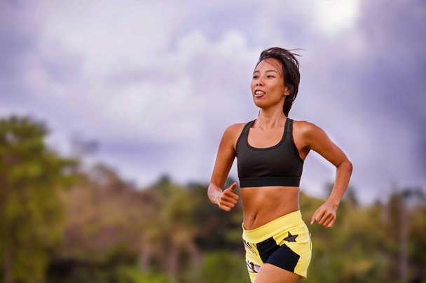 mujer tailandesa asiática en forma y deportiva con entrenamiento corporal atlético al aire libre en entrenamiento de carrera dura en paisaje de campo verde haciendo ejercicio de jogging en fitness deportivo y concepto de estilo de vida saludable
 - Foto, Imagen
