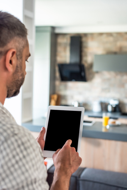 selective focus of man using tablet with blank screen in kitchen - Foto, afbeelding