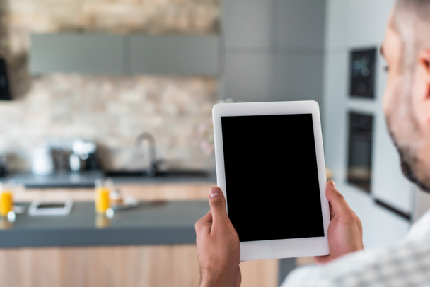 Selektywny fokus człowieka, trzymając tablet z pusty ekran w ręce w kuchni - Zdjęcie, obraz