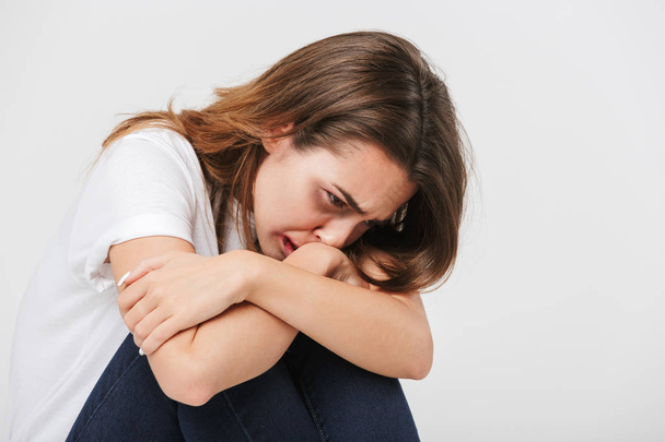 Зловживання налякана жінка з ранами на її обличчі сидить і плаче ізольовано на білому тлі
 - Фото, зображення
