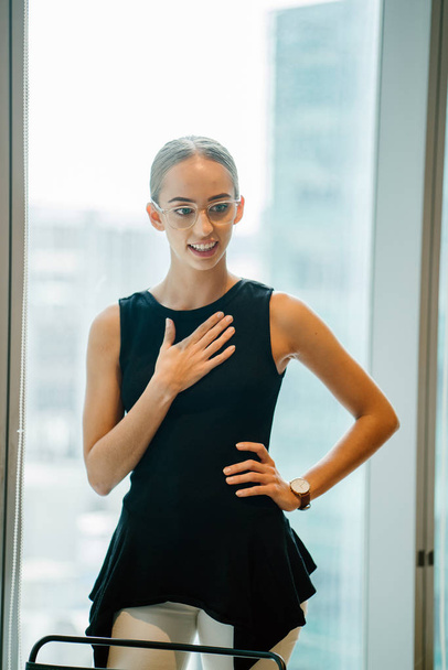 Portrait of young attractive businesswoman wearing eyeglasses standing in modern office  - 写真・画像