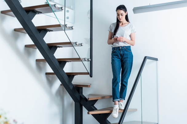 femme utilisant un smartphone tout en se tenant debout sur les escaliers à la maison
 - Photo, image