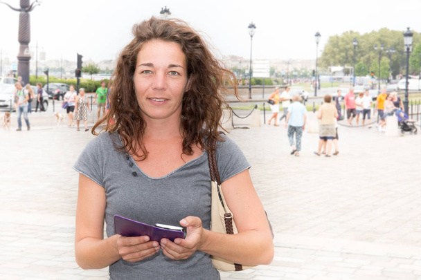 cheerful curly woman on tourist place with smartphone in Bordeaux center in France travel vacation - Photo, Image