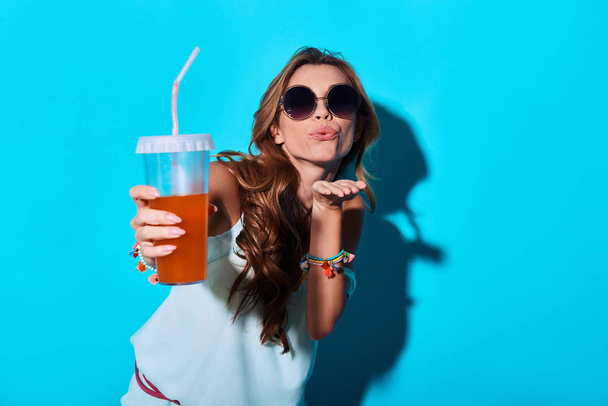 young woman blowing a kiss and toasting with lemonade drink  - Фото, изображение