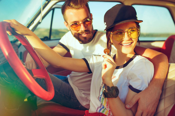 Laughing romantic couple sitting in car while out on a road trip at summer day - Fotoğraf, Görsel