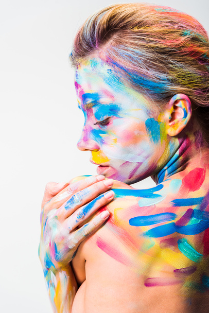 chica atractiva con colorido arte del cuerpo brillante tocando hombro aislado en blanco
   - Foto, Imagen