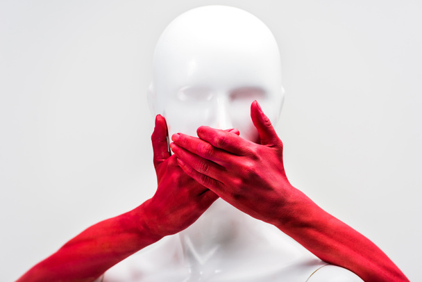 cropped image of woman in red paint covering mannequin mouth with hands isolated on white - Foto, Imagem