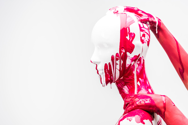 cropped image of girl in red paint touching mannequin head and shoulder isolated on white - Foto, imagen
