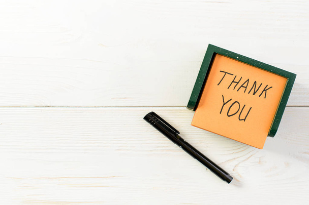 Thank you written on post note sticker with pen on light wooden  - Фото, изображение