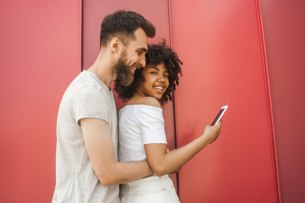 side view of happy young multicultural couple using smartphone on street - Photo, Image