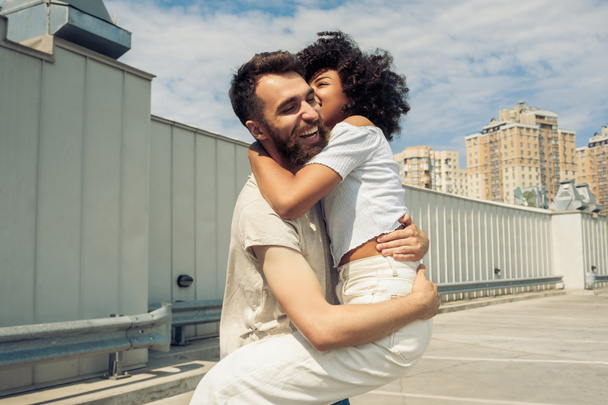 happy young multiracial couple hugging and having fun together on street - Fotoğraf, Görsel