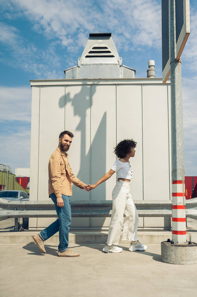 feliz joven pareja multiétnica elegante cogidos de la mano y caminando juntos en la calle
 - Foto, imagen