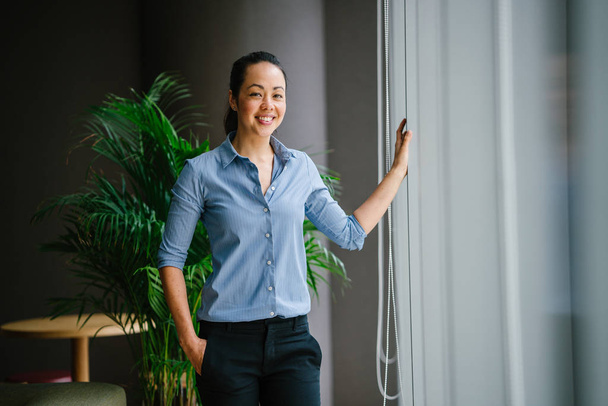 confident asian businesswoman smiling standing in modern office with green plant - Zdjęcie, obraz