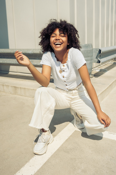 feliz joven afroamericana mujer agachándose y riendo en la calle
 - Foto, imagen