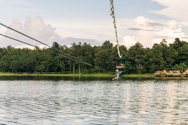 Young woman crossing a lake in zip line - Photo, Image