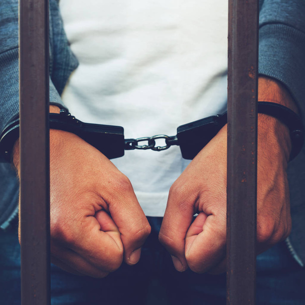 Руки бизнесмена в наручниках за решеткой тюрьмы. C
 - Фото, изображение