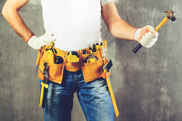 unidentified builder standing in white gloves with a tool belt w - Zdjęcie, obraz