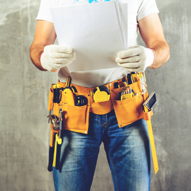unidentified handyman with hand on waist and tool belt with cons - Zdjęcie, obraz