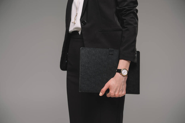 imagem recortada de empresária com relógio de pulso segurando livro didático isolado em fundo cinza
  - Foto, Imagem