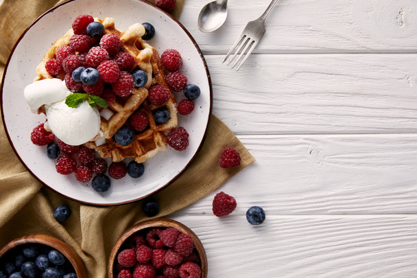 top view of freshly baked belgian waffles with berries and ice cream on white wooden table - Photo, Image