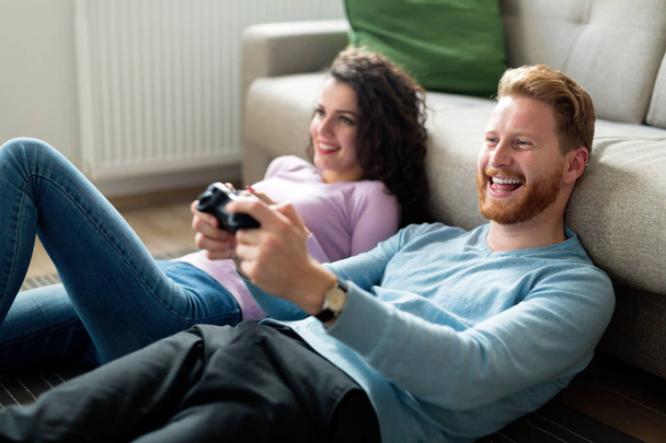 Young attractive happy couple playing video games at home - Foto, afbeelding
