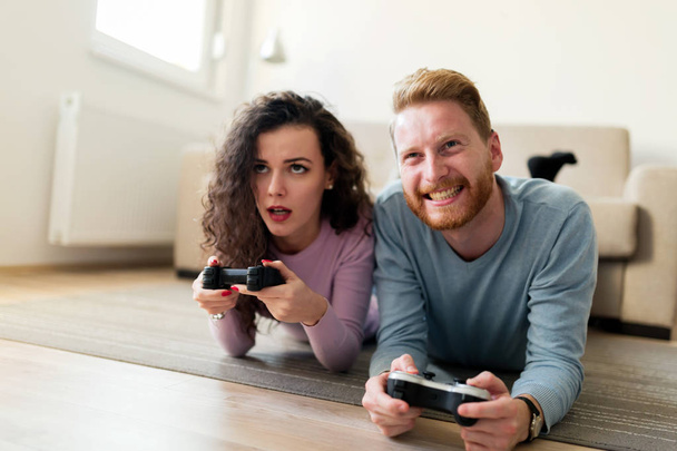 Young attractive happy couple playing video games at home - Фото, изображение