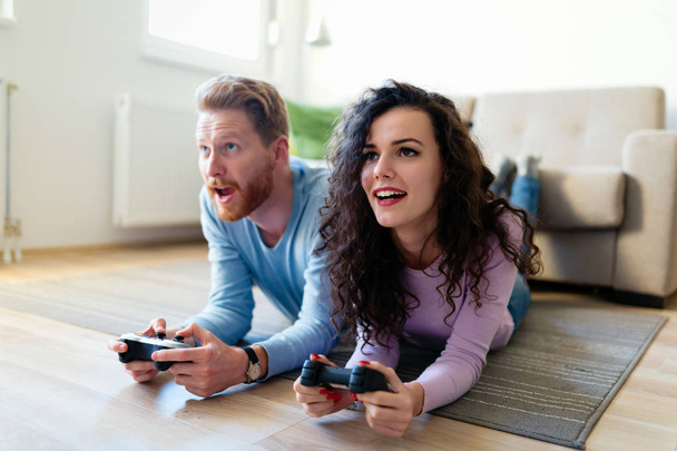 Νέους ελκυστικές ευτυχισμένο ζευγάρι παίζοντας βιντεοπαιχνίδια στο σπίτι - Φωτογραφία, εικόνα
