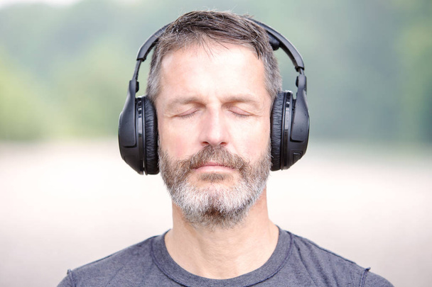 portrait of handsome bearded man with headphones outdoors - Foto, Imagen
