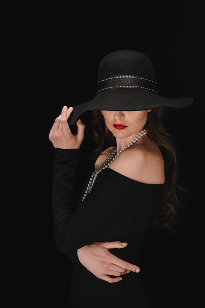 mujer elegante en vestido negro con los ojos cubiertos por paja aislada sobre fondo negro
  - Foto, imagen