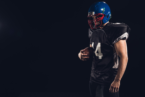 giocatore di football americano in uniforme nera con palla in mano isolato su nero
 - Foto, immagini