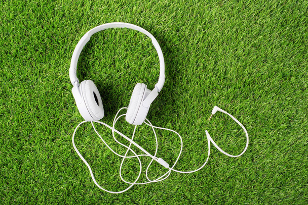 White headphones on a green grass. Top of view - Foto, Bild
