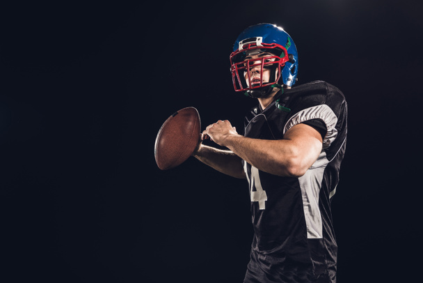 American football speler gooien bal geïsoleerd op zwart - Foto, afbeelding