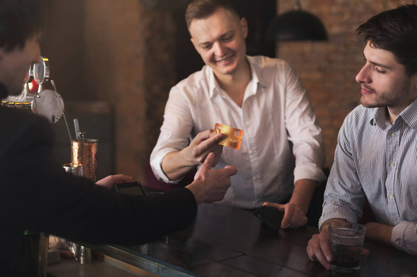 Чоловік дає кредитну картку бармену в пабі
 - Фото, зображення