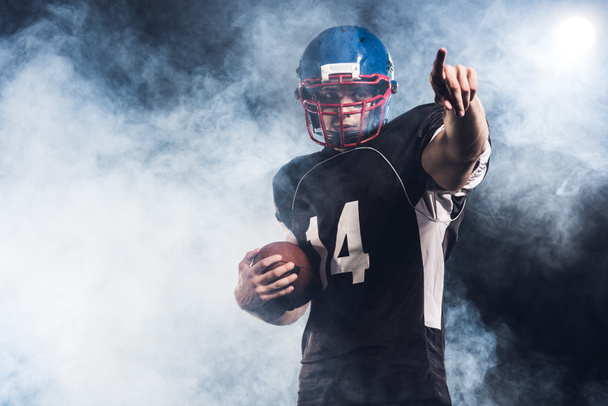 bel giocatore di football americano con la palla puntata da qualche parte contro il fumo bianco
 - Foto, immagini