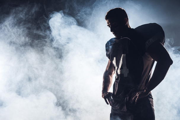 silhouette sombre de joueur de football américain réfléchi regardant vers le bas contre la fumée blanche
 - Photo, image