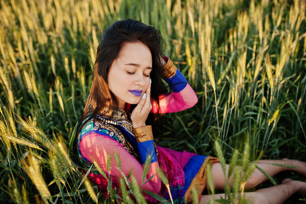 Tenera ragazza indiana in saree, con labbra viola fanno posa al campo al tramonto. Modello di india alla moda
. - Foto, immagini