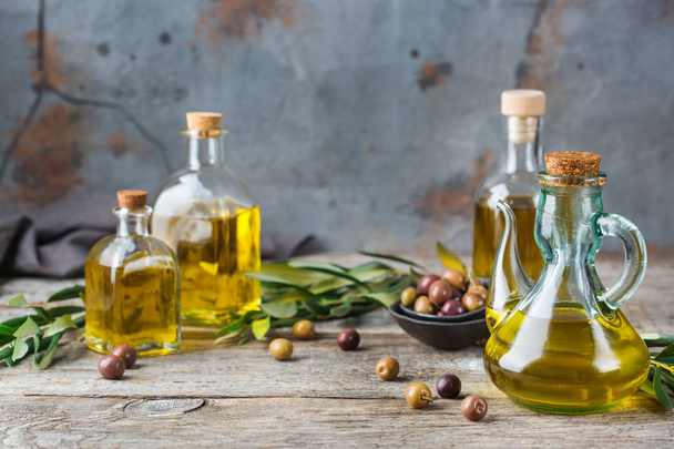 Ernährung und Ernährungskonzept. Sortiment an frischem nativem Bio-Olivenöl extra in Flaschen mit grünen Blättern auf einem rustikalen Holztisch. Kopierraum Hintergrund - Foto, Bild