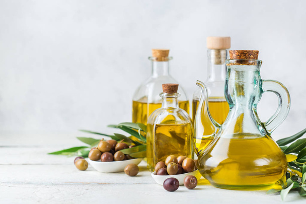 Ernährung und Ernährungskonzept. Sortiment an frischem nativem Bio-Olivenöl extra in Flaschen mit grünen Blättern auf einem rustikalen Holztisch. Kopierraum weißer Hintergrund - Foto, Bild