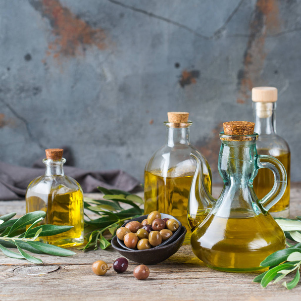 Pojęcie diety i odżywianie jedzenie. Asortyment świeżych organicznych tłoczenia oliwy w butelkach z zielonych liści na rustykalne drewnianym stole - Zdjęcie, obraz