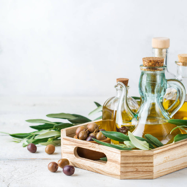 Food diet and nutrition concept. Assortment of fresh organic extra virgin olive oil in bottles with green leaves on a rustic wooden table - Photo, Image