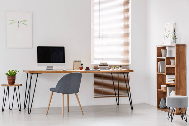Natural and bright office of a start-up company with wooden furniture, desktop computer and gray chair at the desk. Real photo - Fotografie, Obrázek