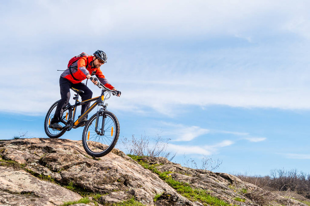Cyclist in Red Jacket Riding the Mountain Bike Down Rocky Hill. Extreme Sport and Adventure Concept. - Фото, зображення